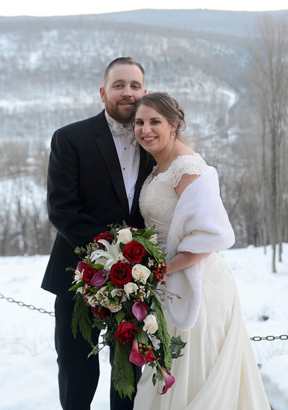 Happy Couple Holding Flowers on a Snow Covered Mountain