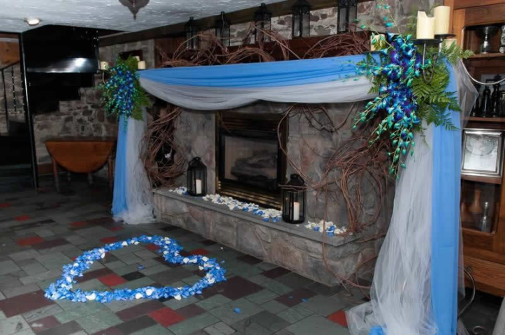 Stroudsmoor Country Inn - Stroudsburg - Poconos - Woodlands Outdoor Wedding - Colorful Sash With Flowers Draping Fireplace - Floral Heart On Floor