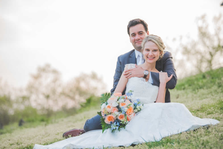 Wedding couple posing, sitting in a field