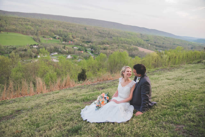 Wedding couple posing, sitting in a field, looking at one another