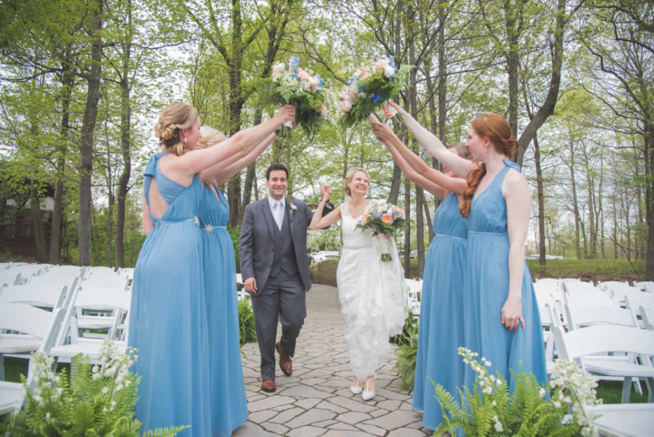 Wedding couple running under a bridge of bride's maid arms