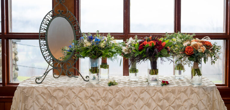 Bridal bouquets rest in vases near a mirror