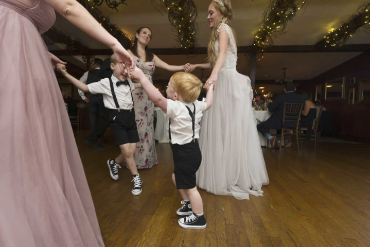 wedding event A bride, 2 women and 2 small boys dance holding hands