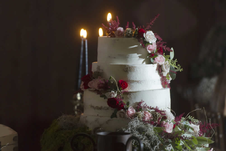 wedding cake A four tier wedding cake in white frosting with cascading red, pink and white roses.