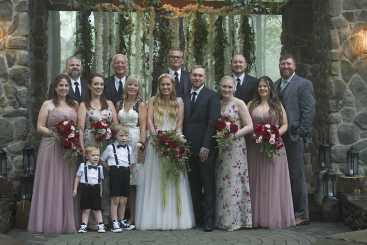 wedding event Wedding party lines up for photograph in front of stone building