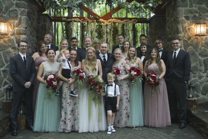 wedding event Wedding party lines up for photograph in front of stone building