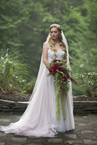 wedding event Full length photo of a bride with long blond curls, holding a bouquet of red roses