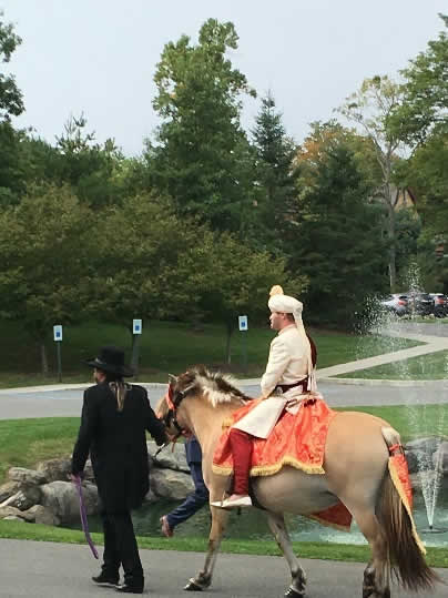 Wedding procession with groom arriving on horseback.