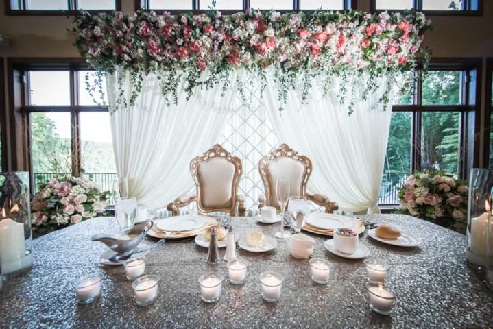 Wedding couple table setting with flowers and draped white fabric