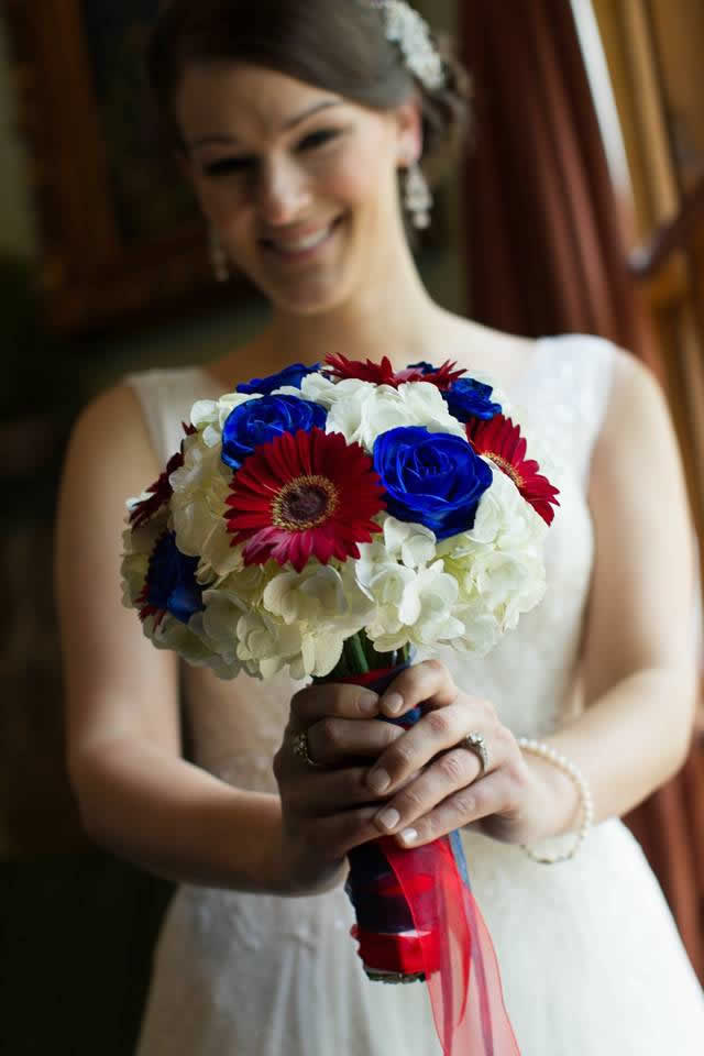 Bride holding red, white, and blue themed flower bouquet