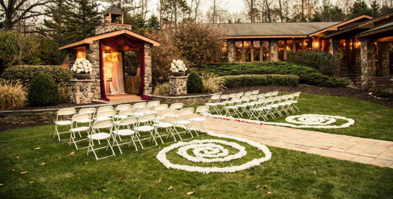 An outdoor wedding ceremony set up with a stone altar and white chairs on the lawn.