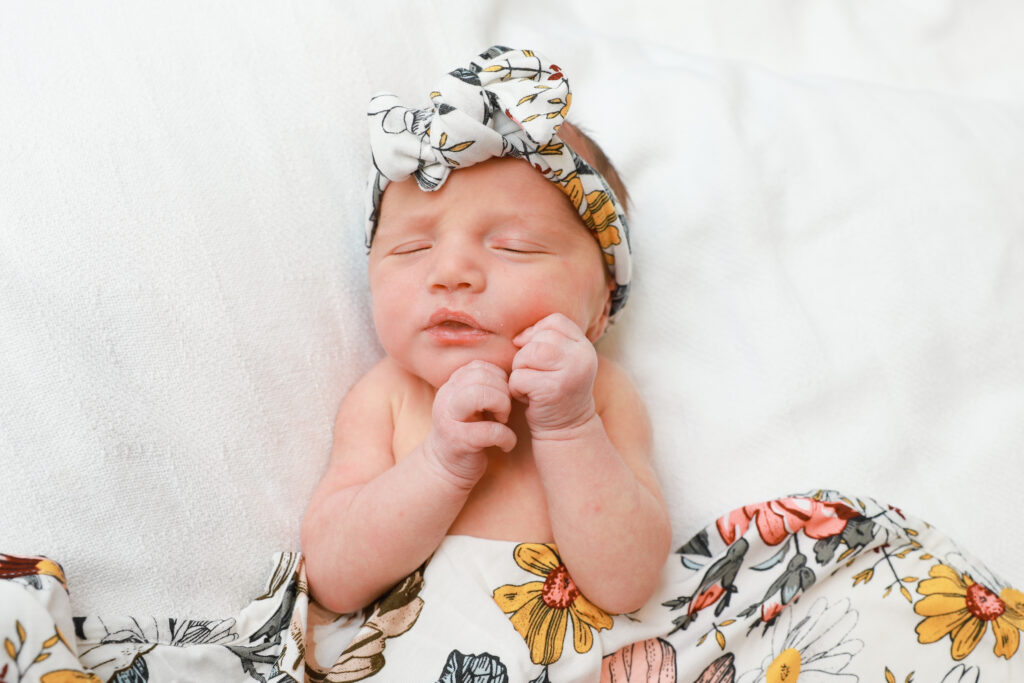 Newborn baby girl sleeps atop white blanket