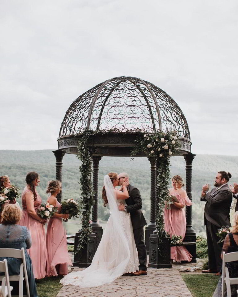 Wedding couple kissing under a scenic gazebo - getting married