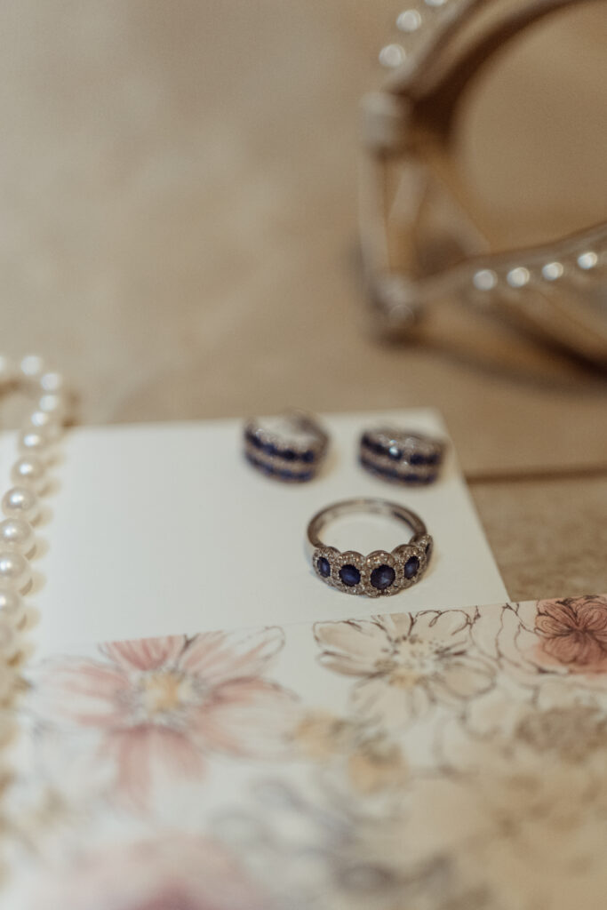 Bride's jewelry rests atop wedding invitation