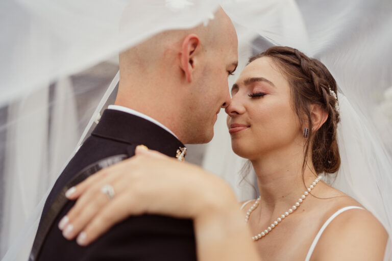 Groom leans to kiss bride beneath veil