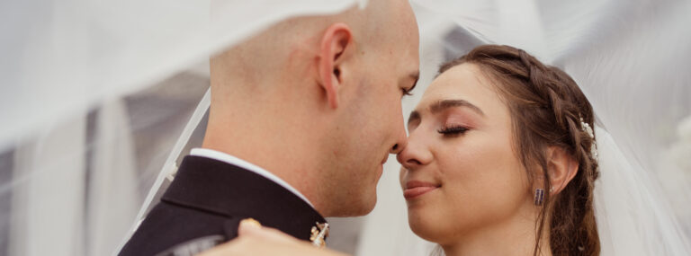 Groom leans to kiss bride beneath veil