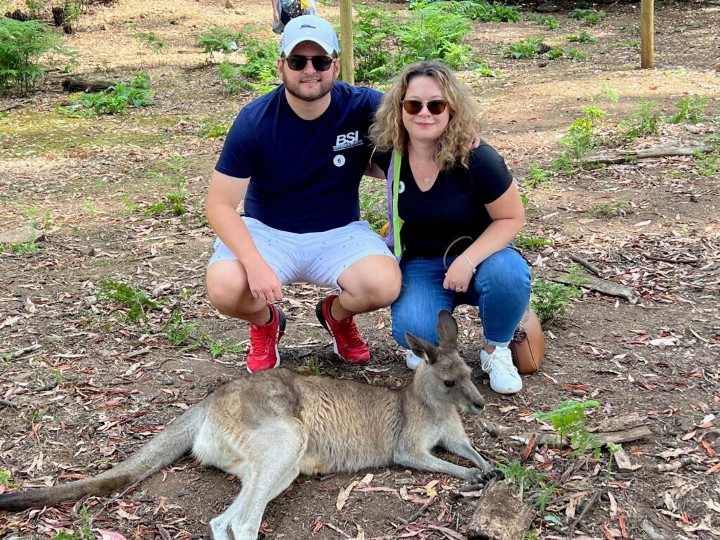 Couple kneels beside kangaroo