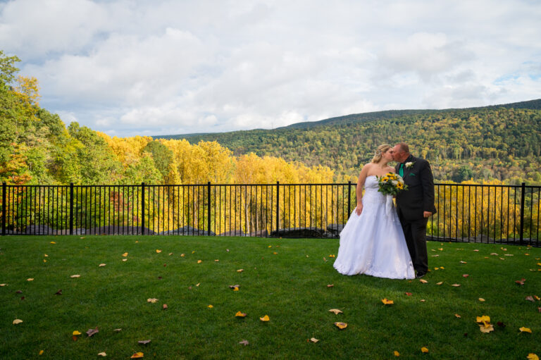 Bride and groom kiss in front of fall mountainscape at Terraview