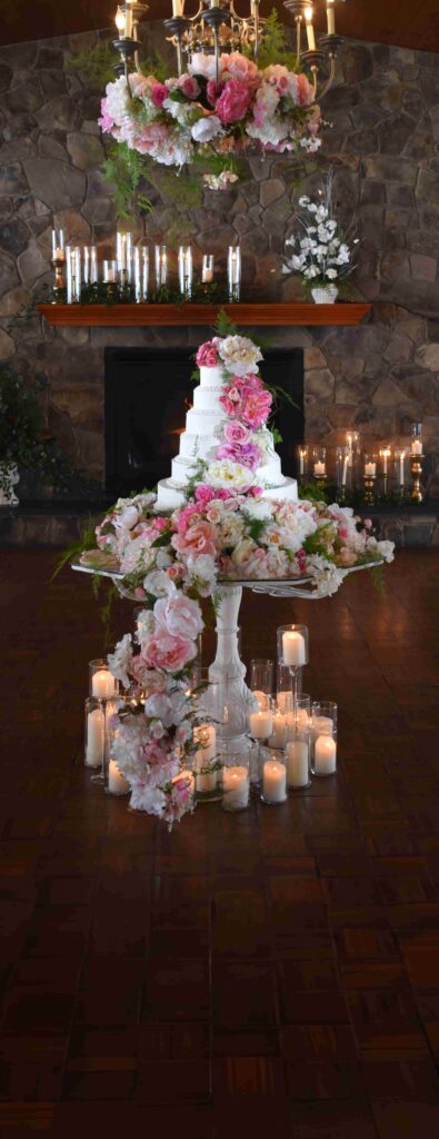 A wedding cake display with pink flowers flowing down to the floor