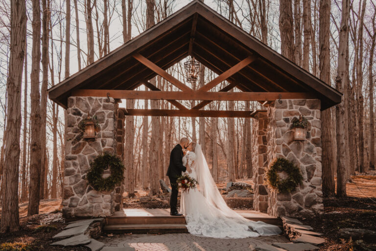 Bride and groom kiss beneath woodland chapel