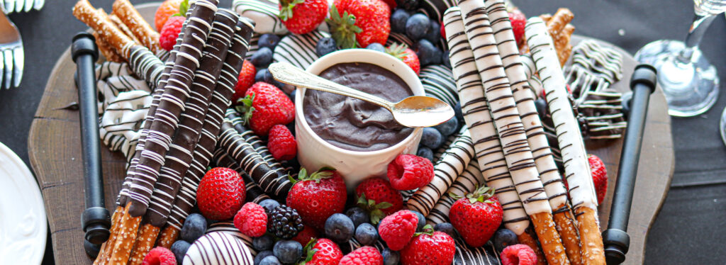 Charcuterie board featuring chocolate-covered pretzels and strawberries