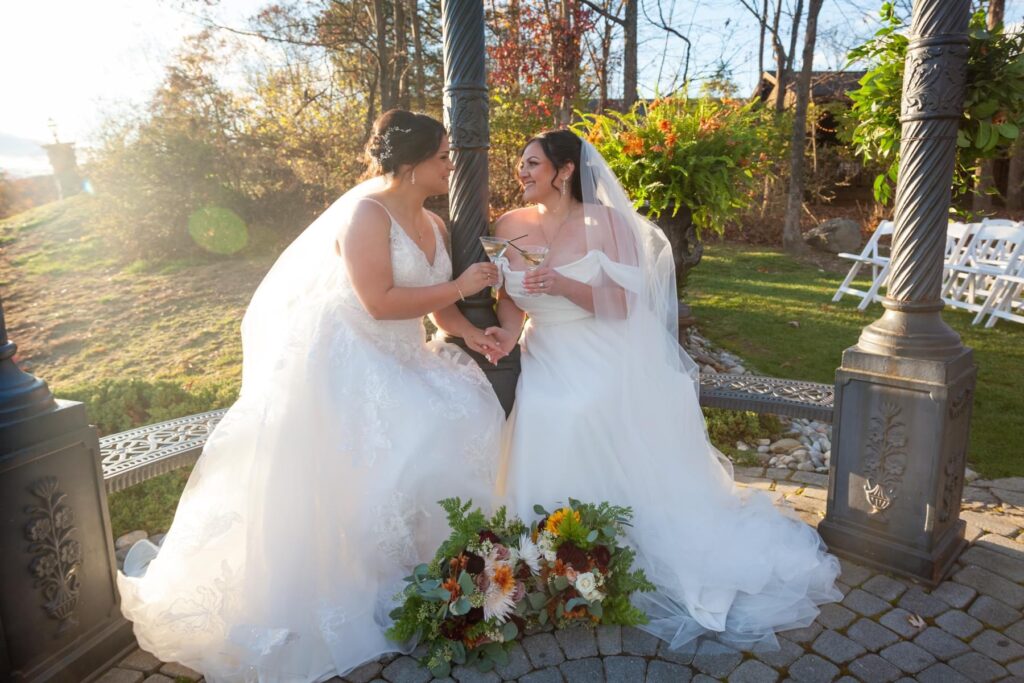 Brides sit on bench together holding hands