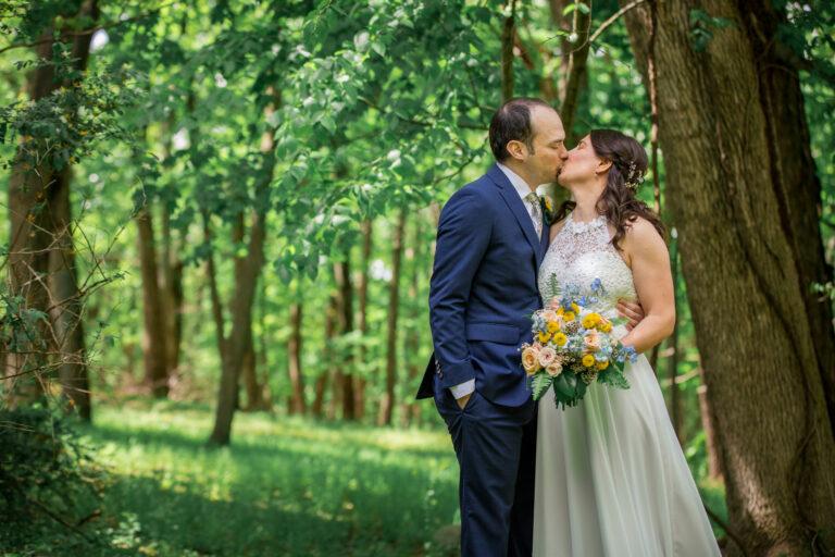 Bride and groom kiss beneath tree canopy